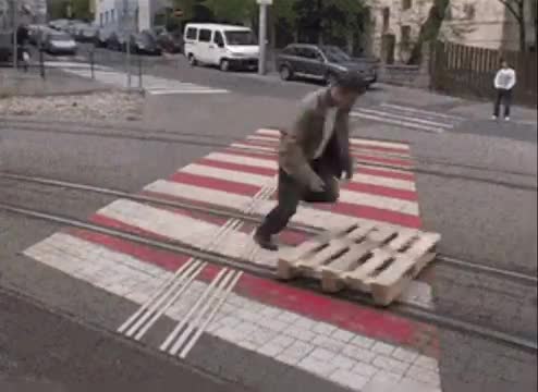 Man glides on tram tracks on wooden pallet